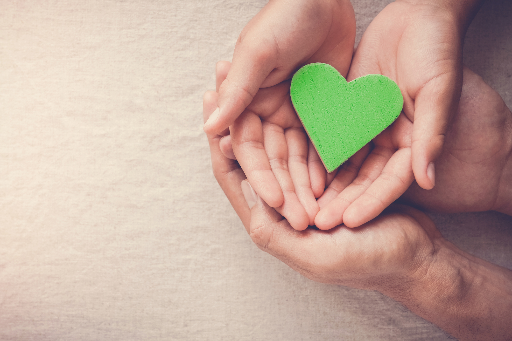 Cartoncino a forma di cuore verde tra le mani